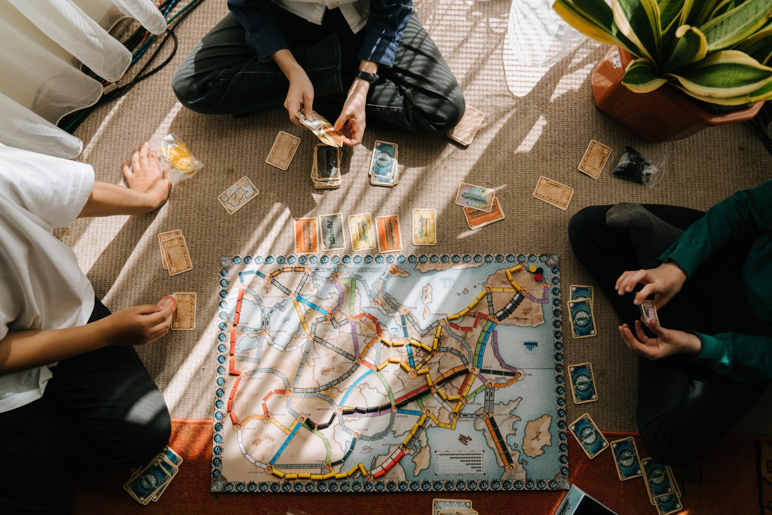 Photo de personnes assises jouant à un jeu de société avec un plateau et des cartes